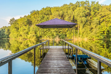 Small wooden pier for pleasure pedal catamaran on the forest lake shore. Dock for pedal boat and a quiet holiday in nature. Disappearing into the distance perspective.