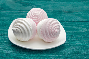 Sweet homemade dessert - berry marshmallow (zephyr) on a plain aquamarine background