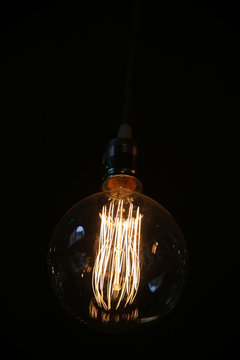 Closeup pf an antique vintage edison style light bulb against dark background