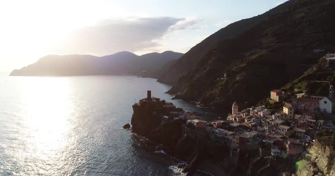 aerial view of travel landmark destination Vernazza, a small mediterranean sea town, Cinque terre National Park, Liguria, Italy. Sunset with cloud and flare. 4k aerial drone down video shot