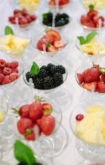 Rows of cocktail glasses with fresh summer fruits and berries prepared for reception
