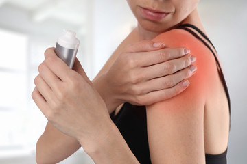 Woman suffering from shoulder back pain applying pain relief cream . Sports exercising injury.