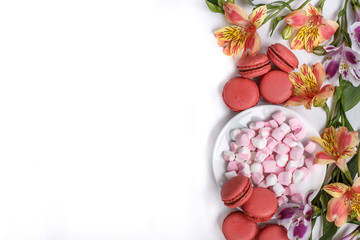 macaroons, marshmallows and flowers Alstroemeria on a white table