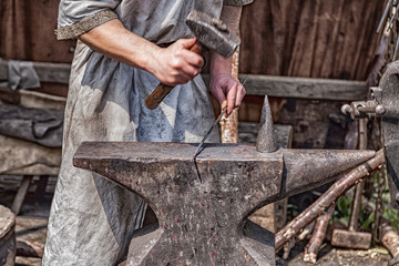 Medieval blacksmith at work with hammer and anvil.