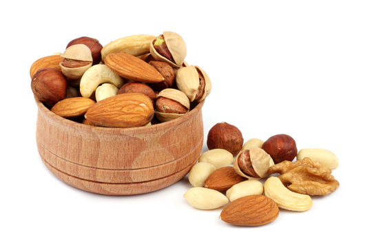mix almonds, cashew nuts, hazelnut, peanuts, walnuts, pistachio in wood plate isolated on white background