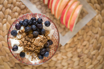 Top view on homemade organic granola and yogurt served with blueberries and sliced apples. Healthy food, snack, breakfast.
