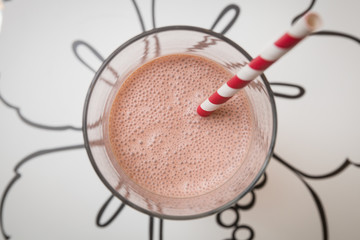 Top view on strawberry protein shake or milk shake in glass with striped straw. Healthy drink and snack. Food concept