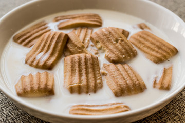 Baby biscuit with milk in white bowl.