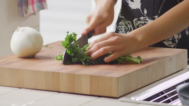 Close up of a woman chopping vegetables in a kitchen