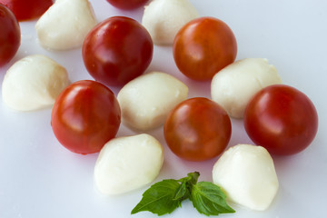 Mozzarella balls and tomato on a white background.