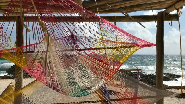 Waves on the rocky shoreline, wind blowing colorful hammocks on the coast, Cozumel Mexico, 4K - 6