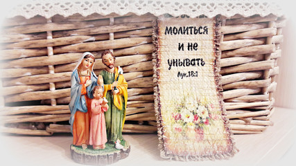  Religious composition: a statuette of Jesus Christ, Mary and Joseph in the background of a wicker basket and text from the Bible "...pray and not to faint" (Luke 18:1) 