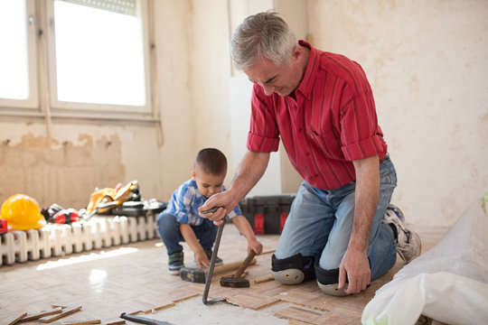 Grandson is helping to his grandfather in separating the old parqet