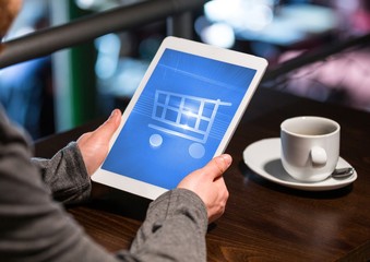 Person using Tablet with Shopping trolley icon and coffee