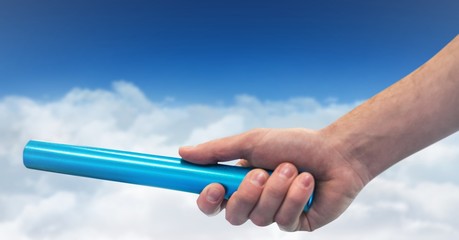 Hand with blue baton against clouds and blue sky