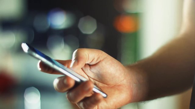 Using a Smartphone, sliding the screen and taping, close up shot with soft bokeh