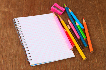 Fototapeta na wymiar Colored pencils, pencil sharpener and notebook