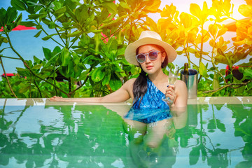 Beautiful young woman in swimming pool with a champagne.