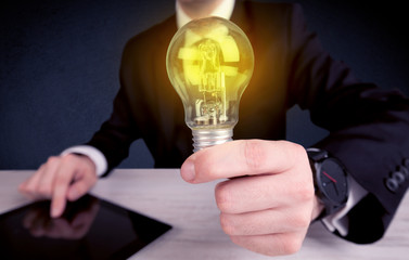 man in suit holding a glowing yellow light bulb