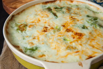 Young cabbage lasagna stuffed with vegetables and rice with bechamel  sauce in ceramic dish on a wooden background. Rustic style.