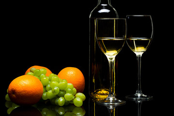 Glasses for wine, grapes and oranges on a black background