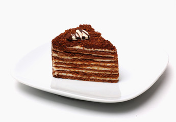 A piece of chocolate cake with cream on a plate on a white background