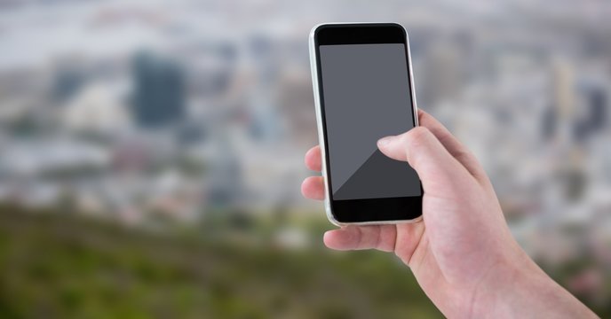 Hand with phone against blurry skyline