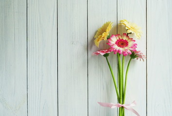 A bouquet of pink and cream gerberas on a white wooden background