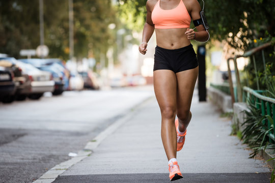 Cropped image of a woman jogger on sidewalk, wearing armband.