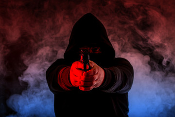 ein Verbrecher steht mit einer Pistole bewaffnet in der Dunkelheit