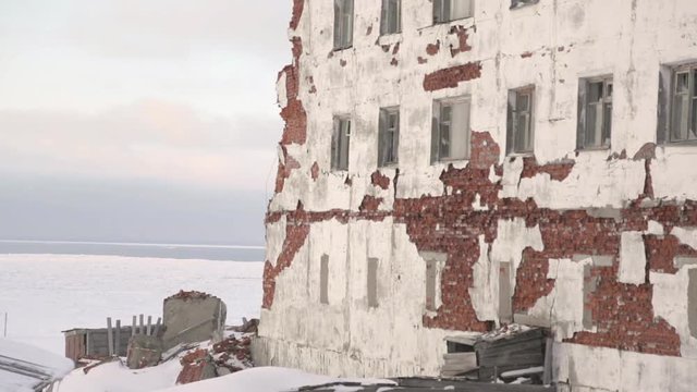 Old abandoned houses with several floors stand on the snowy field background in winter season.  - 6