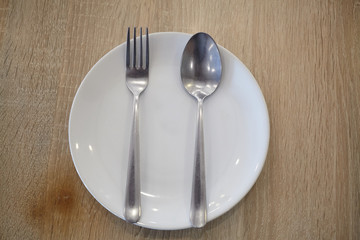 Empty plate with spoon and fork on  wooden background table.