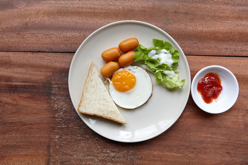 Quick and easy breakfast, fried eggs with sausages, toast and salad.