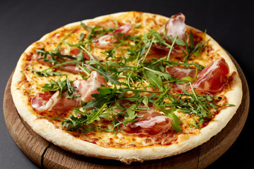 Hot pizza Prosciutto on a rustic wooden table.