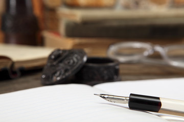 The old penholder for the pen lies on the open notebook. Sharpness on the tip of the pen. Close-up