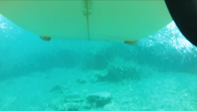 Underwater shots of a Man with his surfboard in the blue ocean