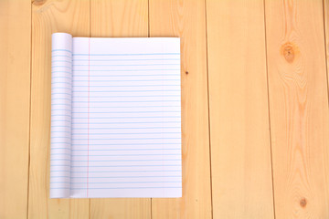 Notebook open to show white paper on wooden background.