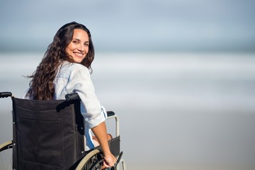 Portrait of woman sitting on wheelchair at beach