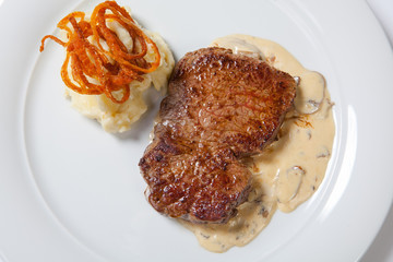 fried steaks with potatoes, fried onion and cream sauce.