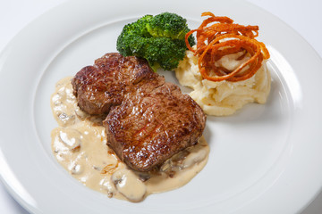 fried steaks with potatoes, fried onion and cream sauce.