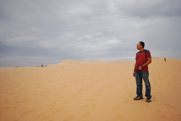 Fototapeta na wymiar Asian Man walking on a desert sand dune in Vietnam, Muine.