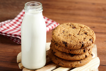 Chocolate chips cookies with milk bottle in background on the wooden table. quick and easy meal in the morning. Close up shot.