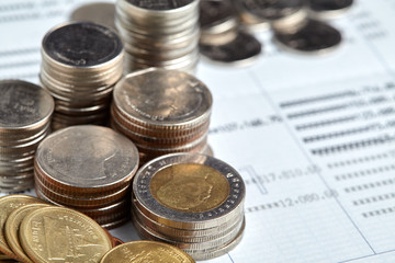 Coins stack with blue home toys on passbook. Saving, income and payment concept.