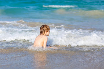 Fototapeta na wymiar little blond kid boy having fun on ocean beach in Florida