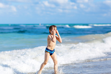 little blond kid boy having fun on ocean beach in Florida