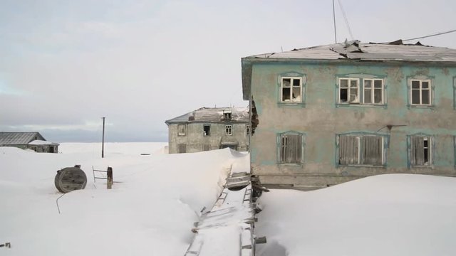 Old abandoned houses with several floors stand on the snowy field background in winter season.  - 4