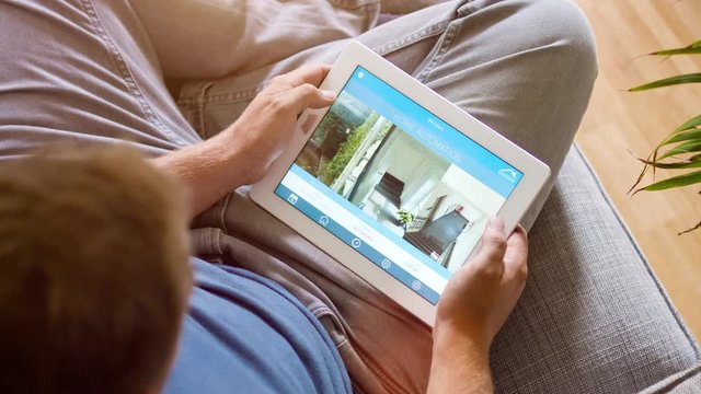 Man Using His Tablet Home Security App and video surveillance at home - 4