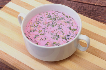 Popular spring cold soup okroshka with yoghurt. Okroshka in a bowl on wooden table. Selective focus
