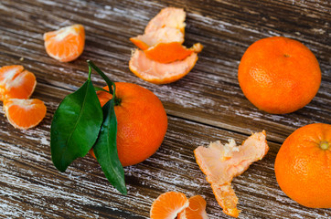 Close up of whole mandarin with leaves,  mandarin slice and mandarin peel on wood table. Organic tangerine fruit background.