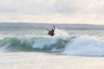 Surfer with a tanned body performs a trick on a short board - a jump over the waves. 